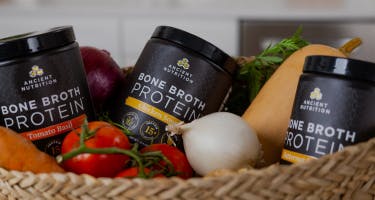 bone broth protein savory bottles behind vegetables